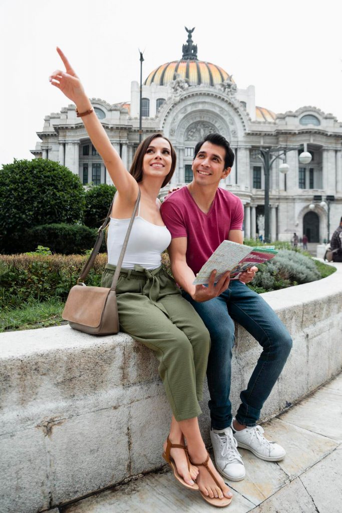 Pareja joven consultando un mapa frente al Palacio de Bellas Artes, ilustrando dónde se puede realizar la subrogación en México.