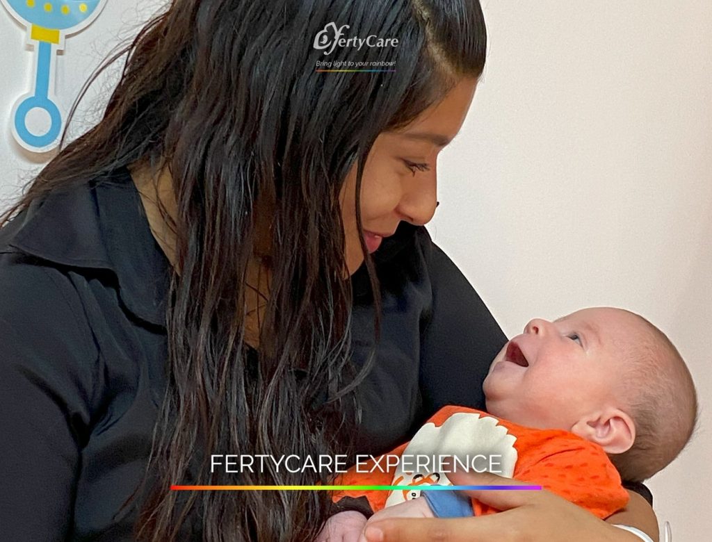 Mujer sosteniendo a su bebé con ropa naranja, mirándose con ternura en FertyCare, representando la experiencia de subrogación.