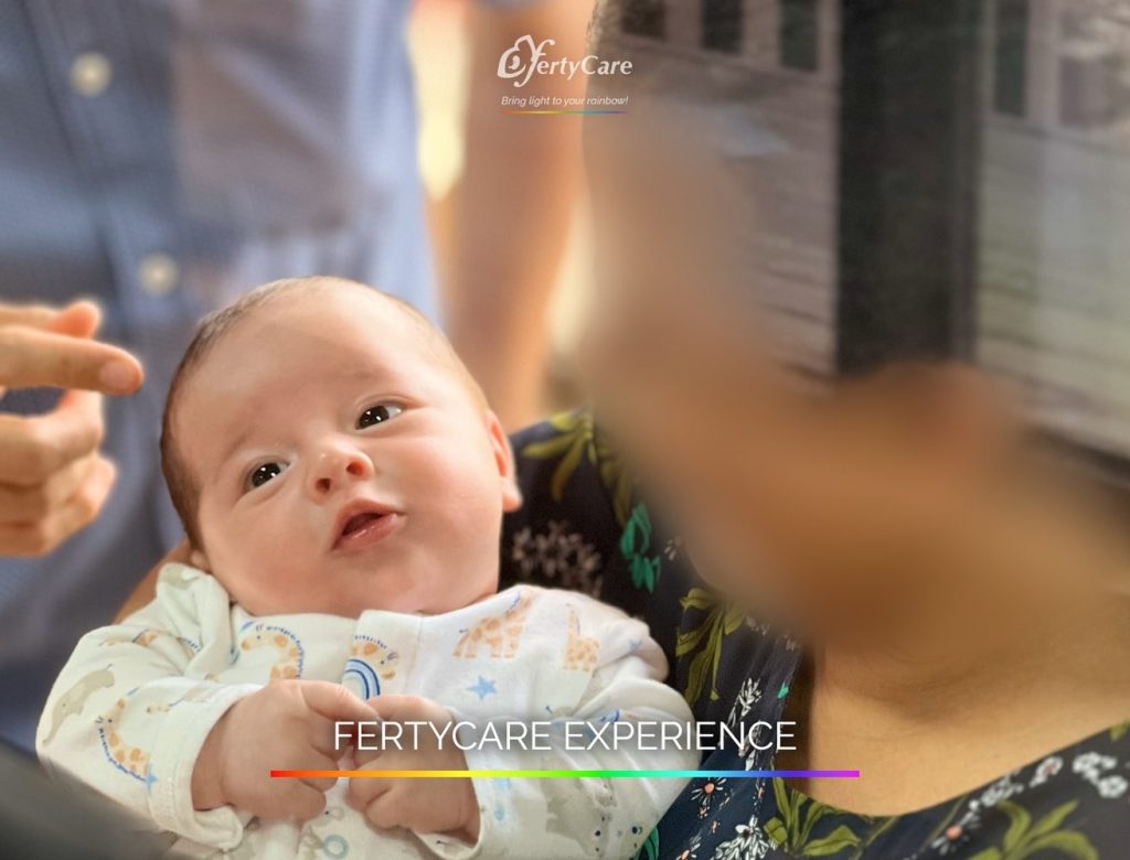 Bebé con ropa estampada, sostenido por un adulto con rostro difuminado, representando la experiencia de subrogación en FertyCare.