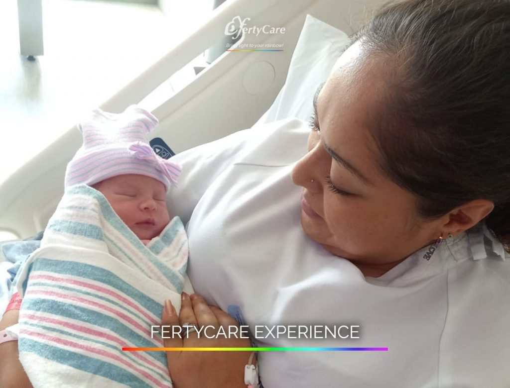 Mujer recostada en una cama de hospital sosteniendo a su bebé recién nacido, representando la experiencia de subrogación en FertyCare.