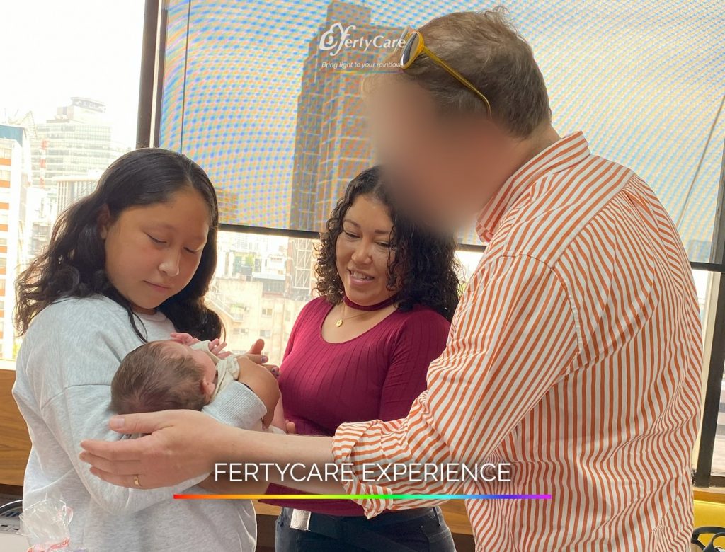 Pareja y acompañante sosteniendo a un bebé recién nacido en las oficinas de FertyCare, representando la experiencia de subrogación.